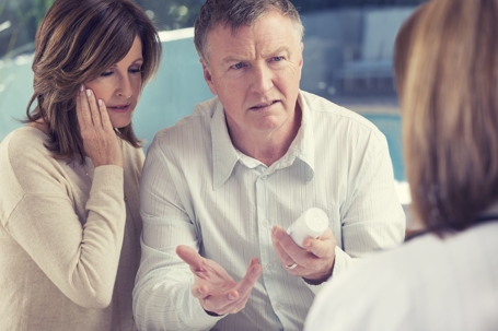 concerned couple with medicine bottle talking to doctor