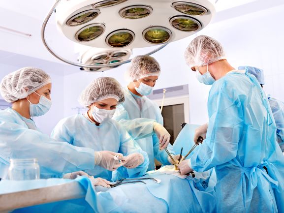 doctors gathered around a patient who is under anesthesia